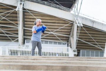 Senior Asian sportswoman boxing while working out on parking outdoors