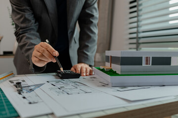 An engineer is calculating whether the structural proportions of a house model are correct with a...
