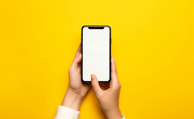 Hands holding a smartphone with a blank screen on a yellow background.