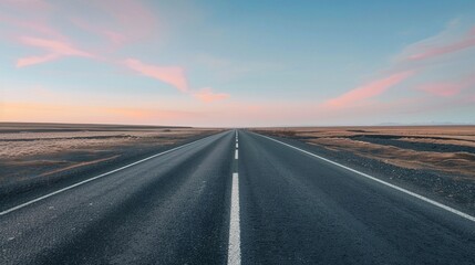 Naklejka premium An open, empty road stretching into the horizon under a wide, uncluttered sky at dawn