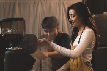 portraits of happiness two waiter teaching woman with apron to use a coffee machine for make a coffee. the happiness men and woman in bakery small business on waiter and waitress uniform.