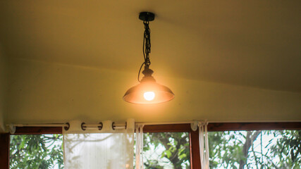 Ceiling lamp in a coffee shop, vintage lamp hanging from the ceiling, window, light shining