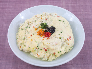 Close-up of steamed egg with chives and red paprika on white dish, South Korea
