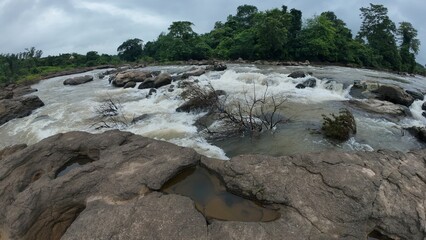 A serene stream flows over smooth rocks, creating a soothing sound of water cascading gently through the landscape.