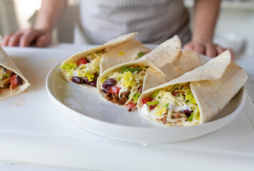 Homemade burritos with ground beef, kidney beans, cheese, lettuce, tomatoes and sour cream