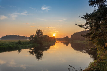 A beautiful sunset over a river with trees in the background