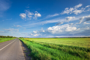 A road with a clear blue sky and a few clouds