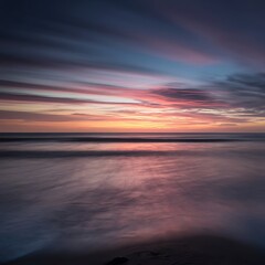 Obraz premium Picture yourself at a beach during sunset. What colors streak across the sky, how does the sound of the waves change as the dayturns to night, and what sensations accompany the cooling evening breeze