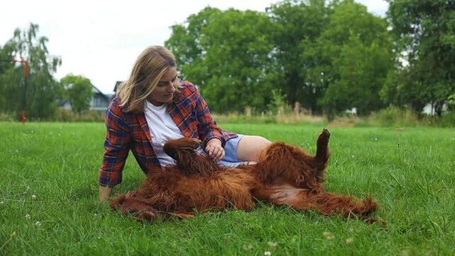 Pretty young girl holding her puppy irish setter dog in the nature, sharing a hug, cuddling, kissing. Animal best friend, lovely friendship. High quality FullHD footage