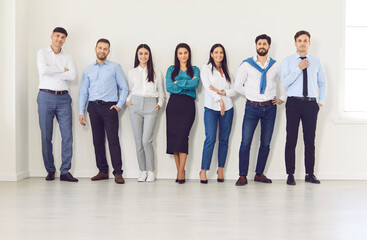 Happy young diverse professional business people team standing looking at camera, smiling workers staff group posing together wearing smart formal wear, human resource, successful office portrait