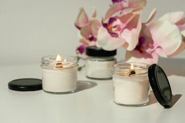 Burning Candles With Pink Orchid Flowers on White Surface
