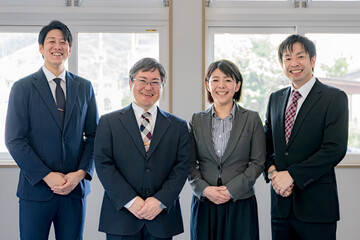 爽やかな笑顔の４人のスーツ男女