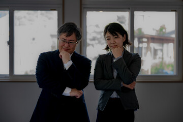 暗い中悩むスーツの男女