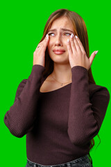 Young Woman Crying With Hands Covering Eyes Against Green Screen Background