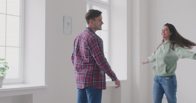 Happy young family couple celebrating the purchase of new home together. The couple embraces happily, excited about their new estate and preparing to relocation as a new chapter in their lives.