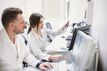 two doctors man and woman doctor examine an MRI image of the brain in an MRI room. Blurred image	