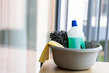a bucket of cleaning supplies on a table against bright clean window , home cleaning equipment,...