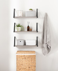 Modern minimalist bathroom shelves displaying towels, toiletries, and small potted plants, a clean and organized space with a natural and serene atmosphere, gray wooden shelves, wicker storage basket.