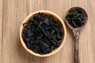 Dried Wakame seaweed or sea mustard in bowl and spoon on wooden background, Table top view