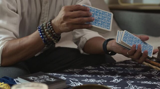 Slow motion shot hands of fortune teller shuffling tarot cards over a table covered with a mystical cloth. Forecasting concept