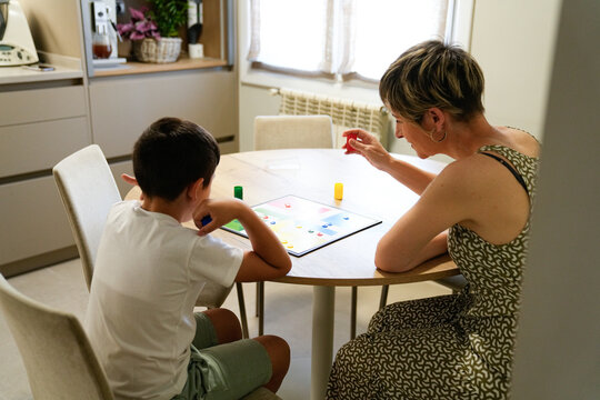 Mother and son focused on a board game in the kitchen