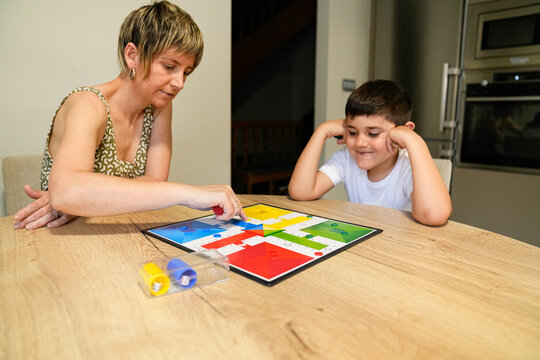 Mother and son playing Parcheesi, focused on game moves.