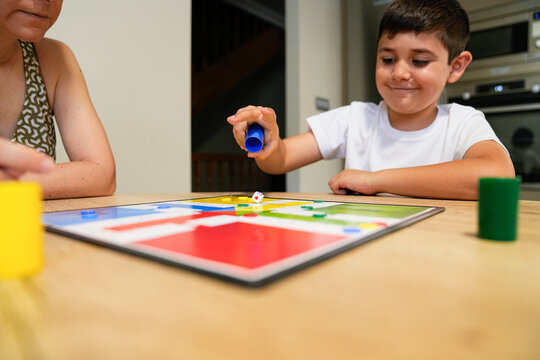 Boy excitedly moving a piece during board game with mother