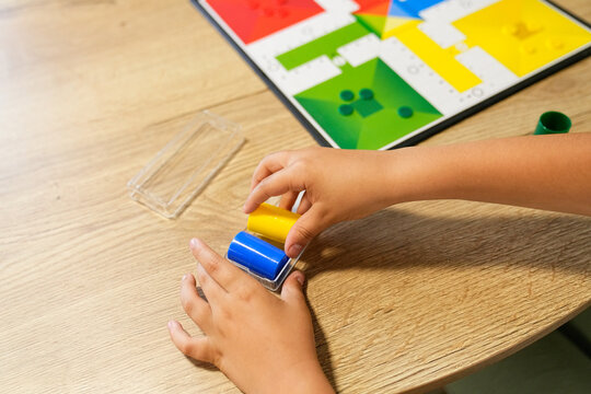 Close-up of hands organizing Parcheesi pieces on the table, preparing for the game.