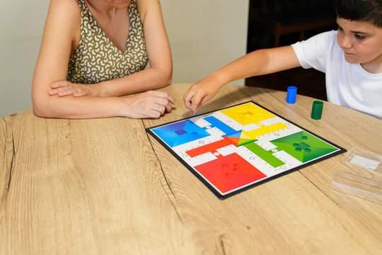 Mother and son strategizing during a game of Parcheesi, enjoying quality time together.