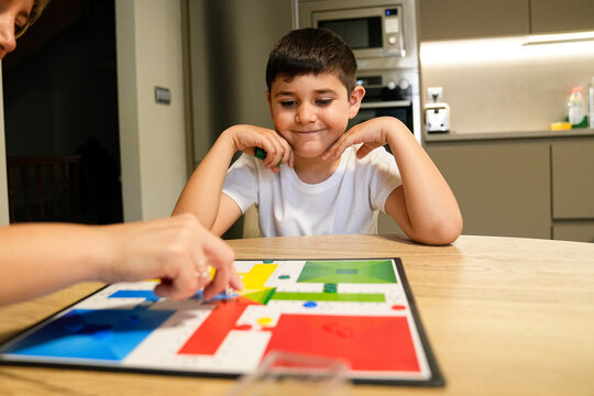 Boy enjoying a board game with his mother at the kitchen table