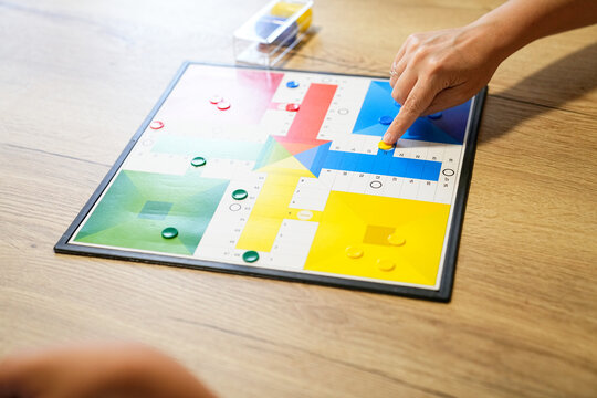 Mother pointing at a spot on the Parcheesi board during a game with her son.