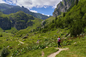 Fototapeta premium Hiker with backpack and poles on a trail in the mountains