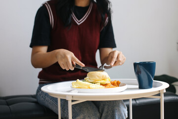 Cropped View Of Young Woman Cutting Tasty Burger With Fork And Knife On Table