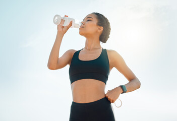 Outdoor, woman and drinking water for fitness on break with exercise, running and workout in Atlanta. Female person, break and sky with sportswear, bottle for health, wellness and wellbeing for jog