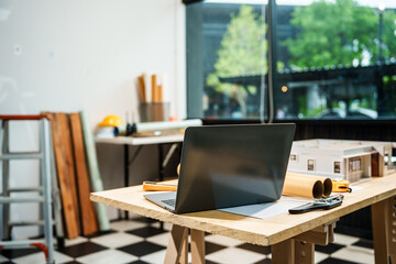 A rear view of a laptop on a desk, displaying an architect's model of a house with various rooms,...