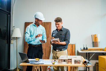 A Caucasian male engineer and an Italian male building contractor are planning and talking at a...