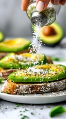 Close-up of Himalayan Pink Salt Shaker Seasoning Avocado Toast on Wooden Surface