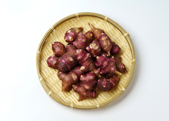 Close-up and top angle view of stacked raw red roots of Jerusalem artichoke on bamboo basket, South Korea
