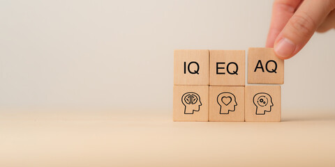 Wooden blocks with the letters IQ, EQ and AQ representing Intelligence Quotient, Emotional...