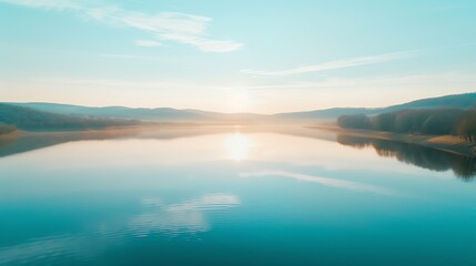 A serene landscape at sunrise reflecting over a calm lake, surrounded by mountains and a clear blue sky.