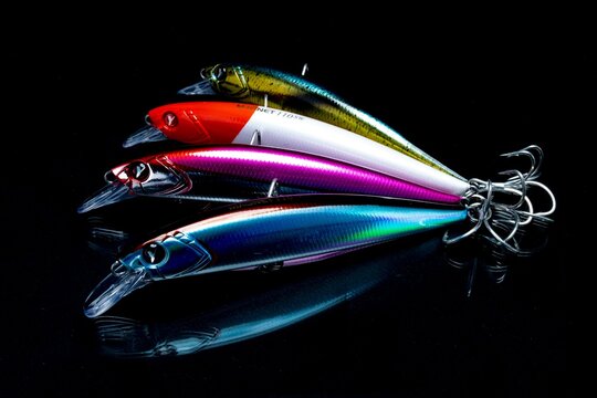 A set of colorful fishing lures arranged on a black reflective surface.