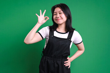 Young Asian Woman Smiling And Showing Ok Sign On Hand Isolated On Green Background