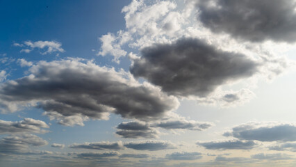 beautiful blue sky with dark dramatic cumulus clouds and sunlight for abstract background