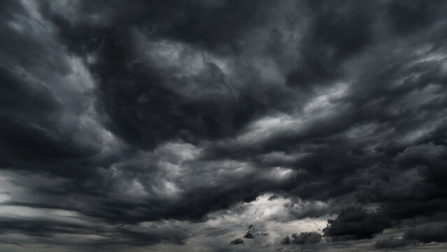 dark dramatic sky with black stormy clouds before rain or snow as abstract background, extreme weather, the sun shines through the clouds, high contrast photo