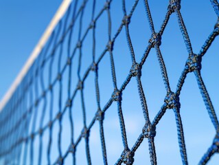 A close-up view of a tennis net with a clear blue sky in the background, suitable for sports or outdoor-themed designs