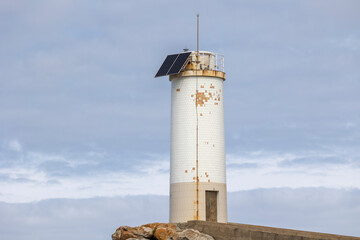 Showcases an old, Roncudo in Corme, Spain weathered lighthouse standing on a rocky coast under a...