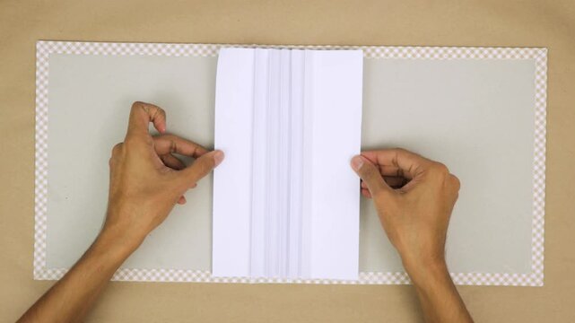 Hands creating a hand-bound book with precision, showing the steps involved in bookbinding