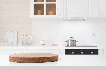 Round wooden pedestal on white table with copy space and defocused kitchen counter background