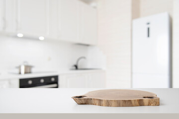 Wooden podium on white table with free space and blurred modern kitchen interior background