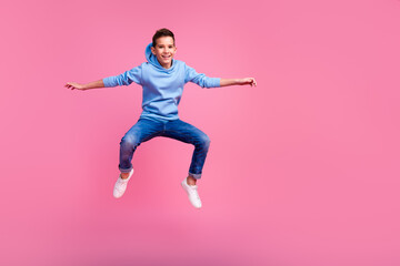 Full length photo of charming teen boy jump surfing dressed stylish blue garment isolated on pink...